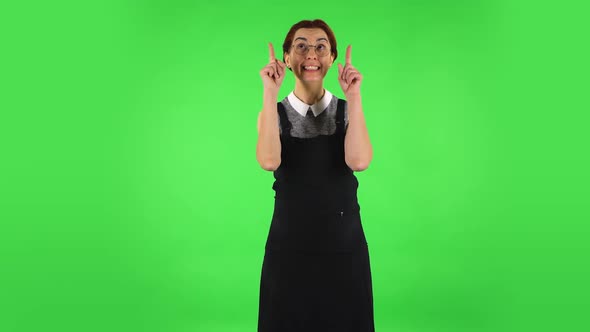 Funny Girl in Round Glasses Is Pointing Up Fingers. Green Screen