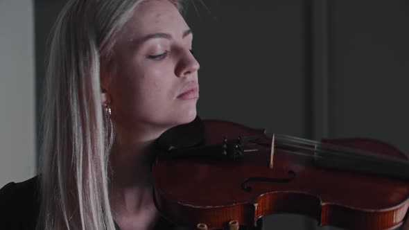 Young Woman Teacher Violinist Puts the Violin on Her Shoulder and Looking in the Camera