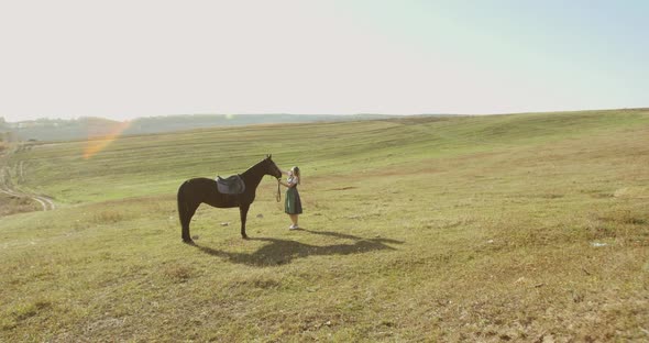 Slavic Woman in a National Dress Stands By a Horse and Admires It Among Steppes