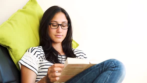 Young woman relaxing and reading a book on the sofa