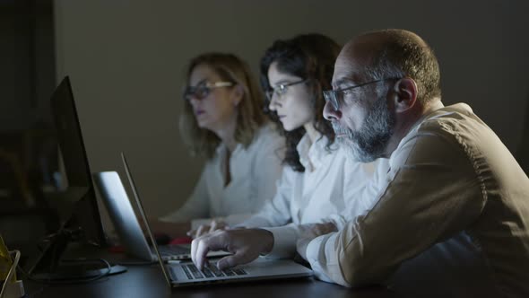 Tired Business People with Laptops in Dark Office