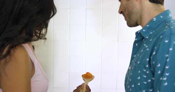 Woman feeding man while cooking in kitchen