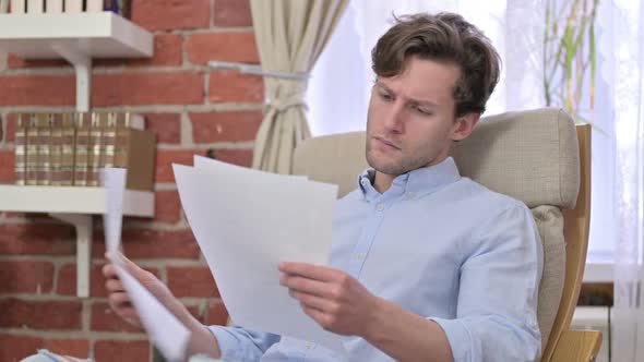 Young Man Reading Documents in Office