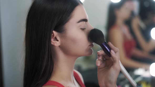 Side View of the Hand of a Makeup Artist Applies Powder