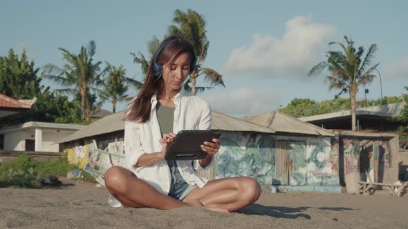 Woman with Laptop Sitting on Sand