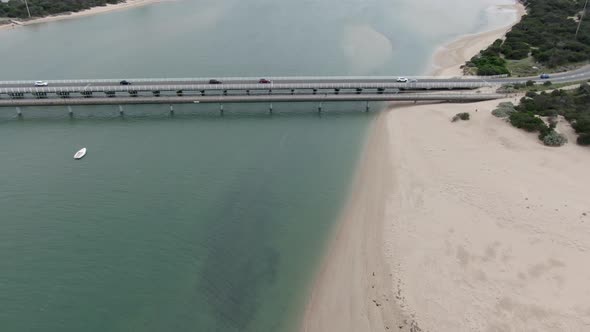 AERIAL TRUCK LEFT Vehicles Crossing River Bridge At Costal Town