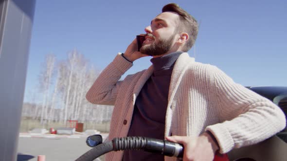 Man Chatting on Phone while Refueling Car