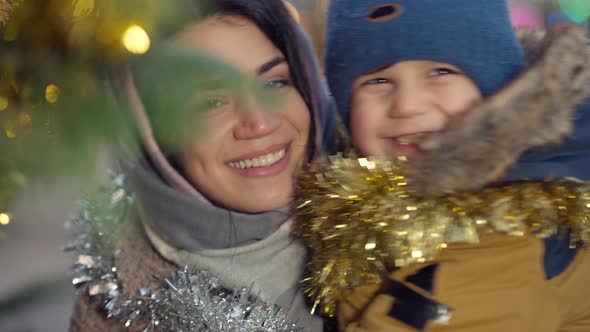 Closeup Smiling Woman and Boy with Hazel Eyes Smiling Looking at Camera with Christmas Lights in