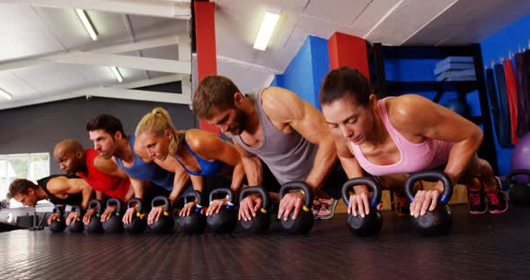 Group of people performing push-up exercise with kettlebell