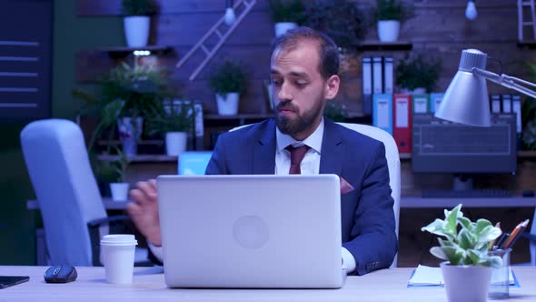 Businessman Sips Coffee While Working Late at Night