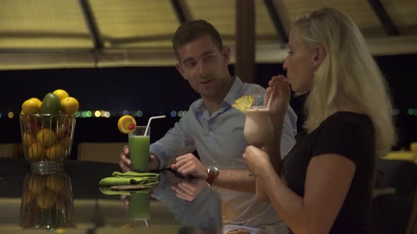 A man and woman couple have a drink at a bar at a resort