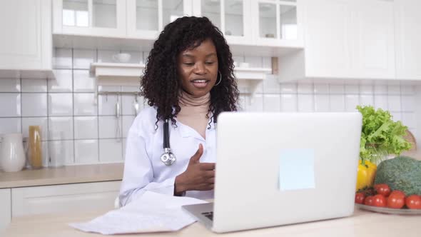 A Black Female Doctor Is Teaching at Home Using a Video Call Application on Her Computer. The