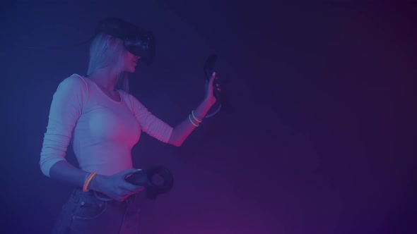 Side View of a Girl in Virtual Reality Headset, Standing in the Room with Neon Lighting Colors