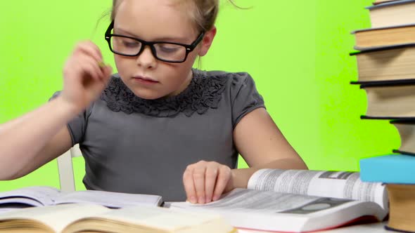 Little Girl in Glasses Looking in Books Information. Green Screen