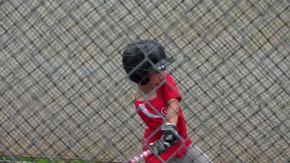 A boy practices baseball at a batting cage with a red white and blue American flag bat.