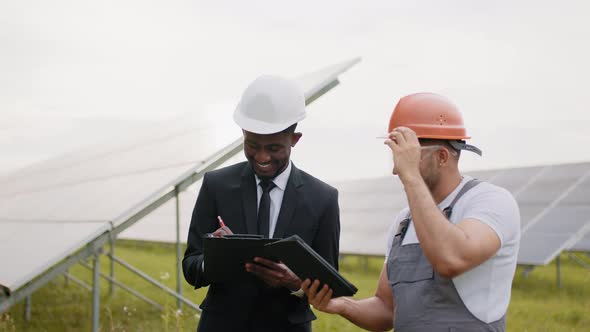 Technician and Inspector Standing Among Solar Plant