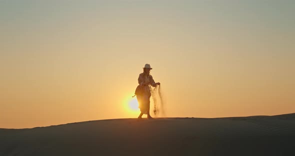 Happy Woman with Sand Blowing Away By the Wind with Golden Sunset on Background