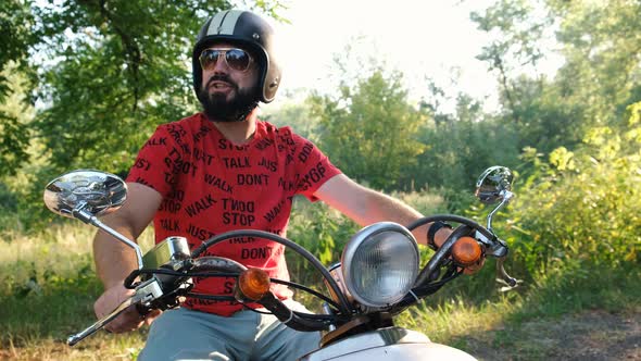 Handsome Hipster Accelerating on Old Vintage Scooter. Bearded Twists Motorbike Throttle. Test-drive