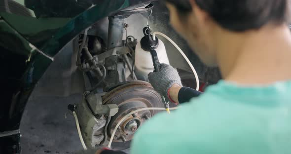 Auto mechanic replacing brake fluid on a vehicle