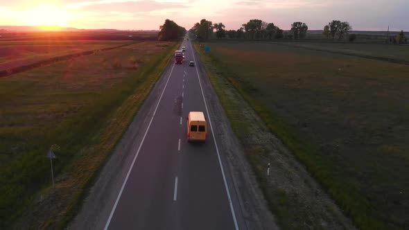 Aerial shot: flying along road with driving vehicles, trucks and cars.