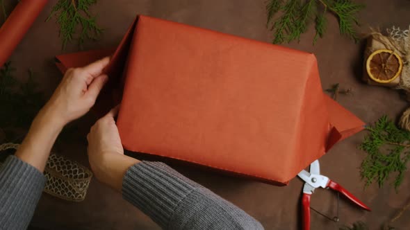 Female Hands Wrapping Christmas Gift Box with Kraft Paper