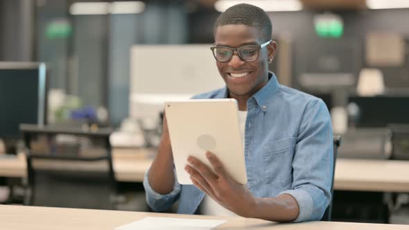 Successful Young African American Man Celebrating on Tablet in Office