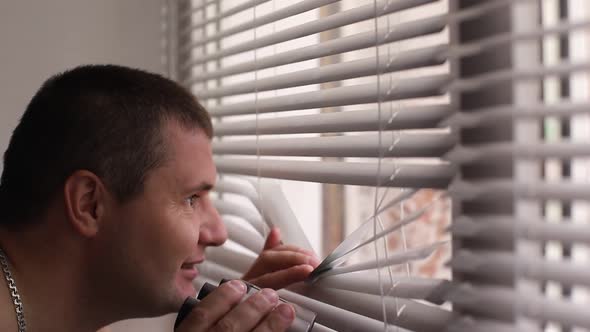 Man Spying on People Using Binoculars for Observation