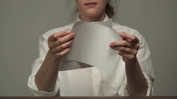 Young Woman Wearing White Shirt Tearing a Paper Into Pieces