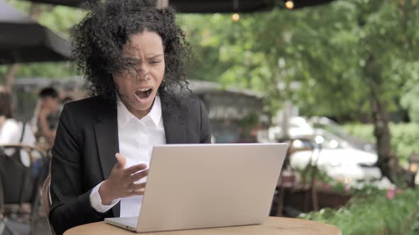 African Woman Upset by Loss, Sitting in Outdoor Cafe