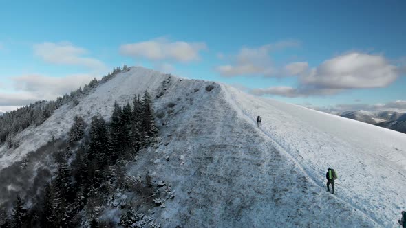 Drone Following Group of Hikers, Ascending a Summit in Winter