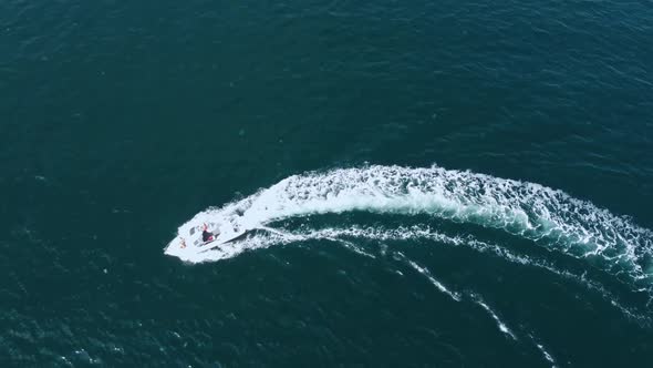 Aerial view of a speedboat moving in a circle for a turn, with a man and two girls on board
