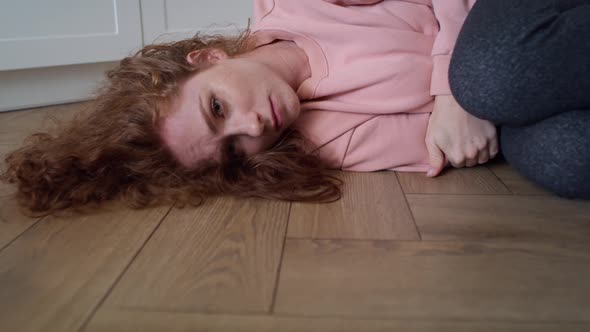 Zoom in video of depressed young caucasian woman lying in the floor.