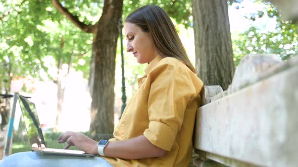 Happy Female Freelancer Enjoying Remote Work Sitting in the Park Smiling Woman Using Laptop