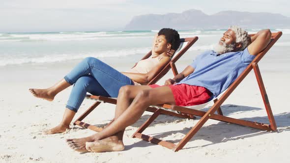 African american couple lying on sunbeds on sunny beach