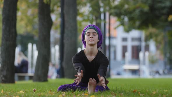 Calm Concentrated Young Islamic Muslim Woman Girl in Hijab Sitting in Park on Grass Outdoors Doing