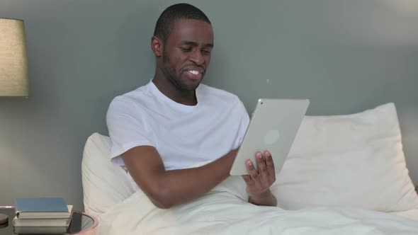 Online Video Chat on Tablet By Young African Man in Bed