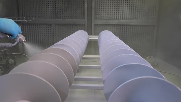 Man applying white Teflon wear resistant spray coating to two large rotor drills in factory