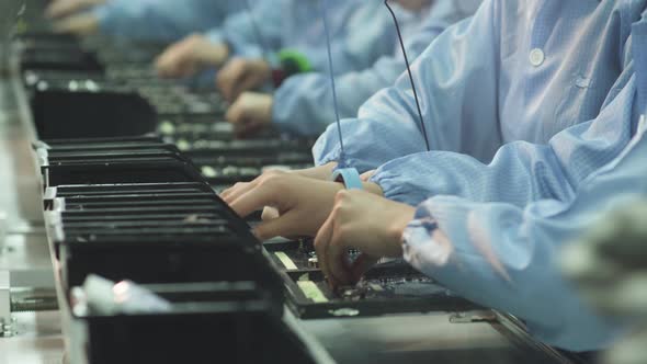 Workers install elements on an electronic circuit board at a TV factory