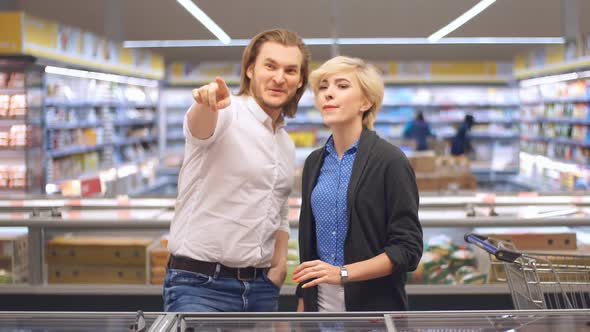 Young Happy Couple in the Supermarket Choosing Products for a Family Celebration