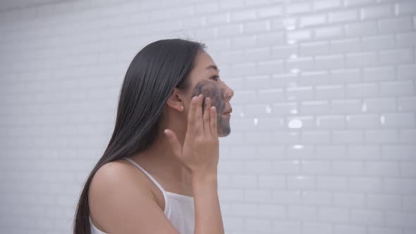Beauty concept. A young Asian woman is putting mud on her face, 4k Resolution