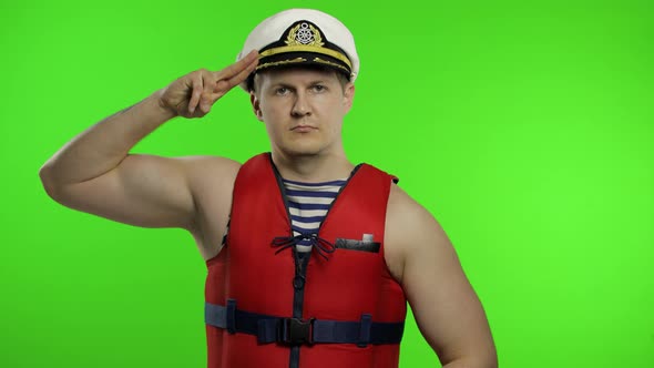 Muscular Sailor Man Works As Lifeguard at Beach Salutes with Hand To Camera