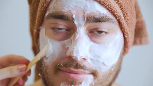 Cosmetologist Applies Mask with Spatula on Face of Man