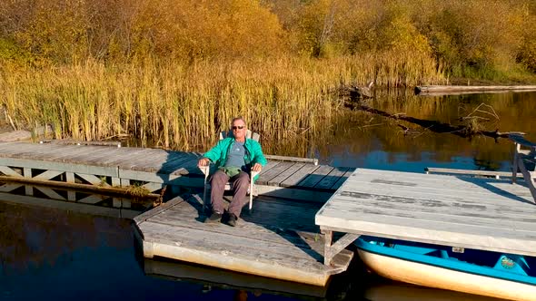 Man sitting on dock at sunset