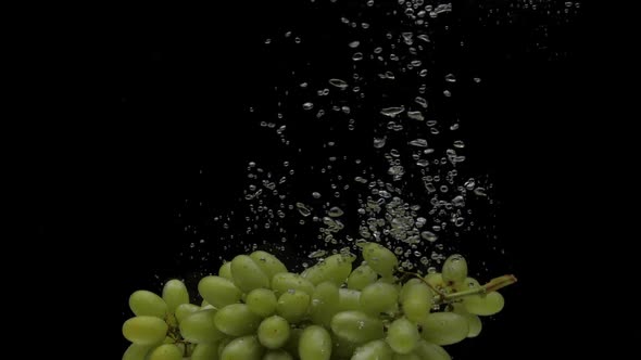 Slow Motion Green Grapes Falling Into Transparent Water on Black Background