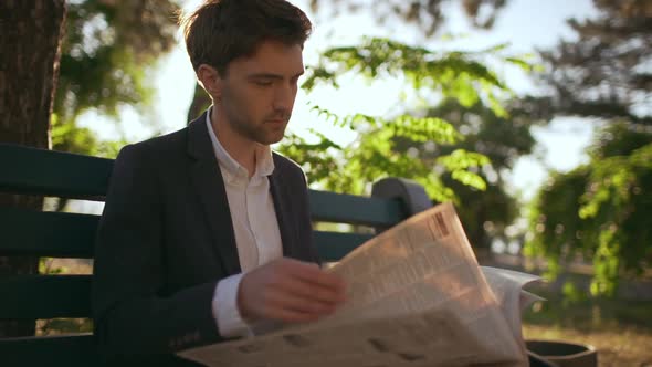 Close Up Slow Motion Male Entrepreneur Business Man Sitting on Bench in Green Sunny Park Reading