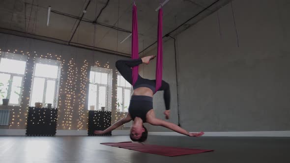 Aerial Yoga  a Young Woman Hanging in a Hammock with Her Head Upside Down