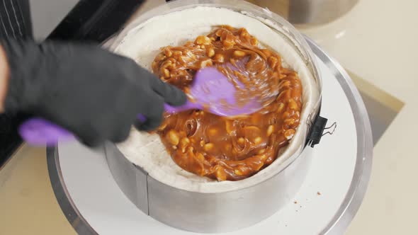Pastry Chef Smears Caramel with Peanuts Above Vanilla Cream