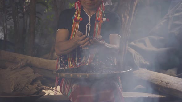 A karen tribe woman hands holding roasted coffee bean on threshing basket at wooden kitchen
