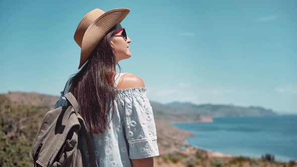 Rear View Tired Happy Woman Tourist Pulling Up Backpack on Shoulder Standing on Top Mountain