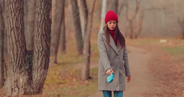 Girl in a Hat and Coat is Walking Through the Woods a Walk with a Pet